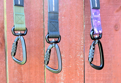 Three dog leashes with carabiners hanging on a wooden surface